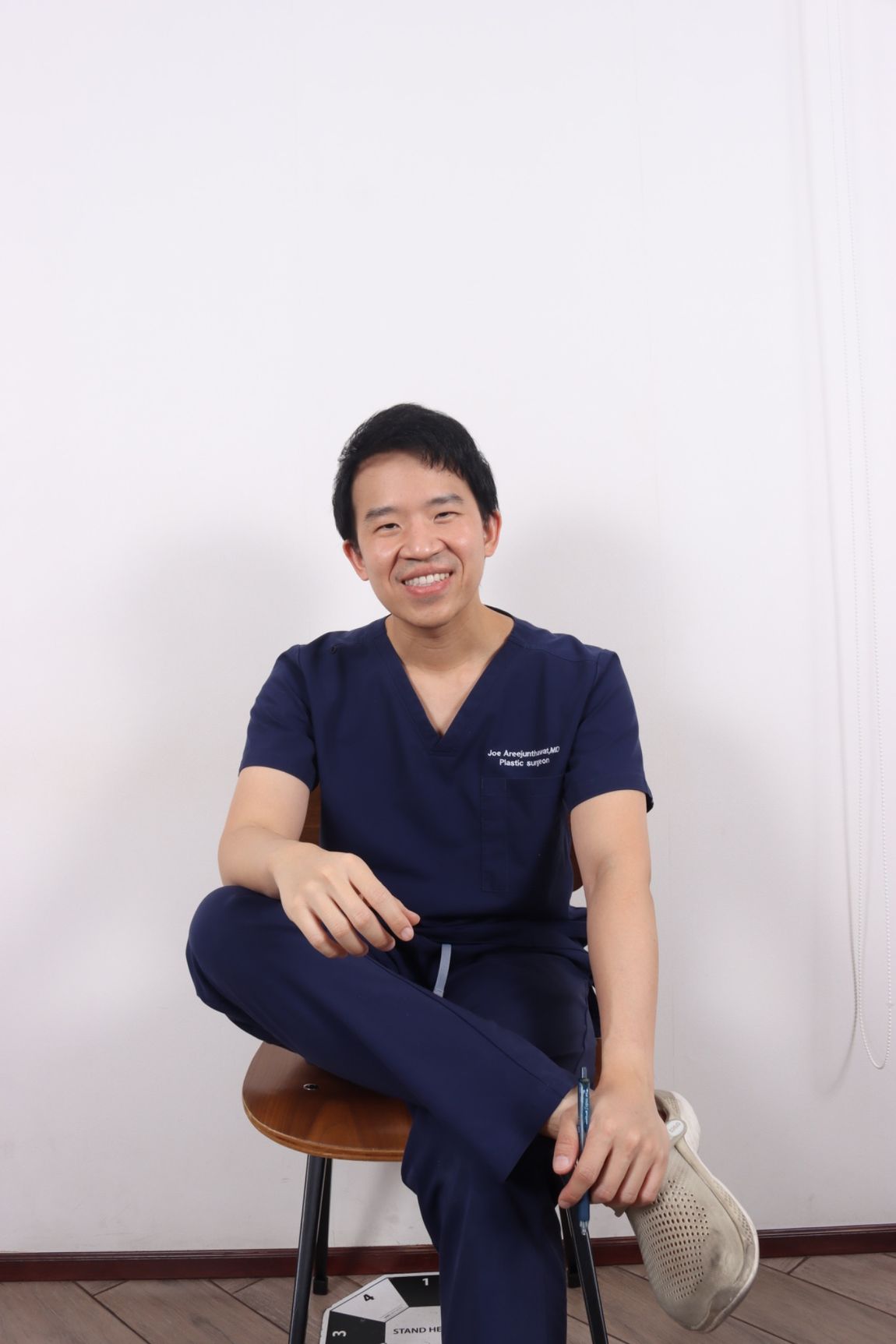 Dr. Joe Areejunthawat seated in navy surgical scrubs