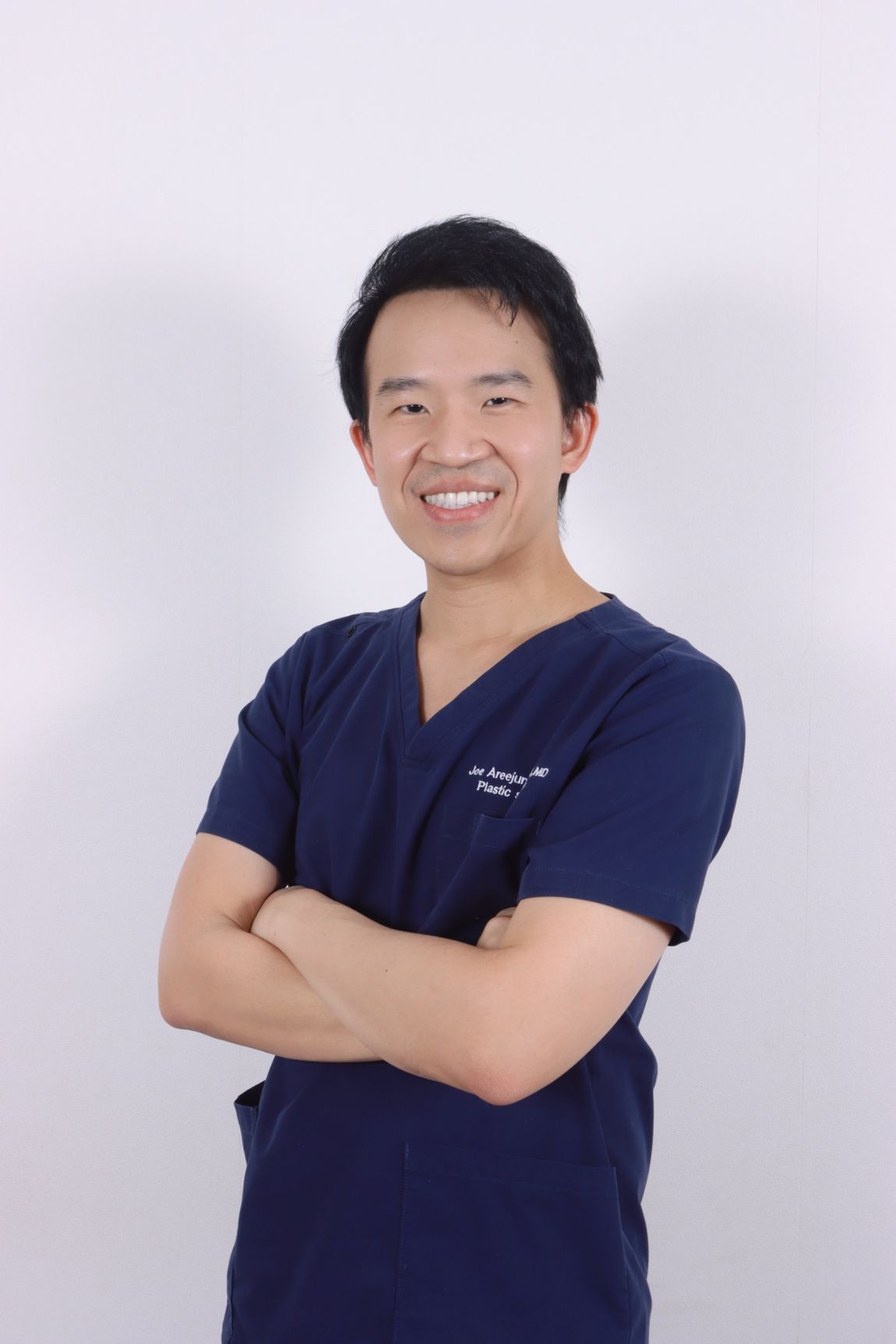 Dr. Joe Areejunthawat in navy surgical scrubs
